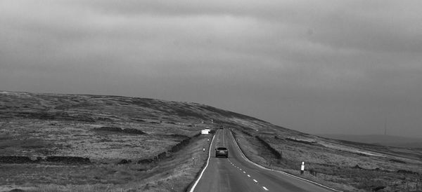 Road leading towards mountains against sky