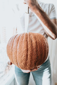 Midsection of man cutting pumpkin