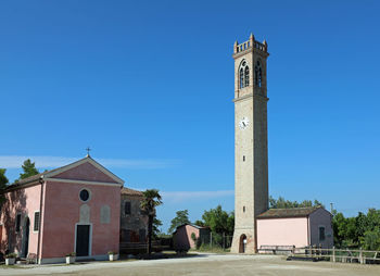 Tower amidst buildings against clear blue sky