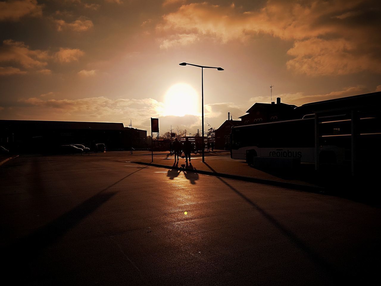 SILHOUETTE MAN ON ILLUMINATED ROAD AGAINST SKY DURING SUNSET