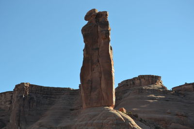 Low angle view of rock formation against clear blue sky