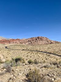 Scenic view of road through desert against clear blue sky. red rock canyon, nevada 