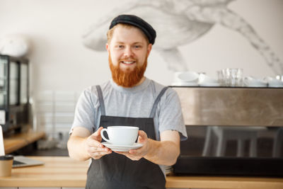 Portrait of young man with coffee standing at home