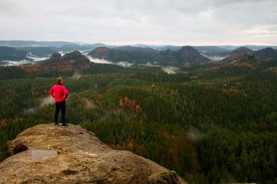 Runner in pink jacket and light black trousers. ginger hair sportsman take a rest in rocky mountains