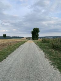 Road amidst field against sky