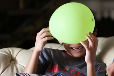 Close-up of boy playing with balloons at home