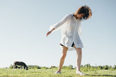 Full length of woman with dog on field against sky