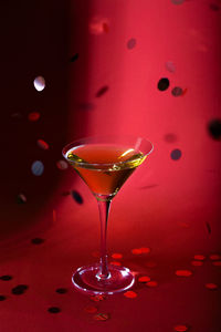 Close-up of wineglass on table against illuminated background