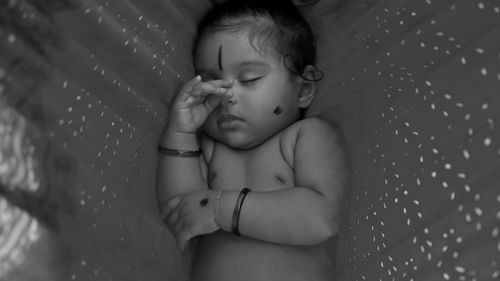 High angle view of shirtless baby girl sleeping on hammock