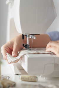 Cropped hands of tailor using sewing machine