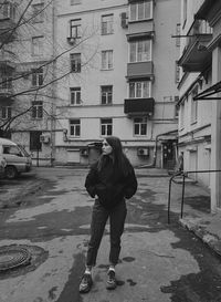 Rear view of man standing on street amidst buildings