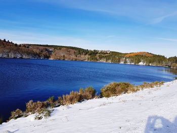 Scenic view of lake against blue sky during winter