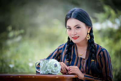 Portrait of young woman drinking water in park