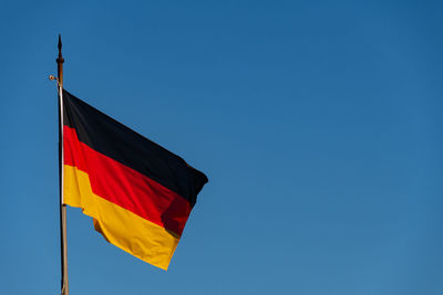 Low angle view of flag against blue sky