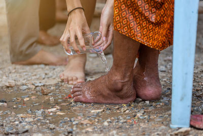 Low section of woman pouring water on female friend feet