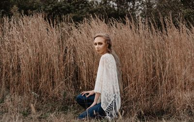 Portrait of young woman kneeling on field