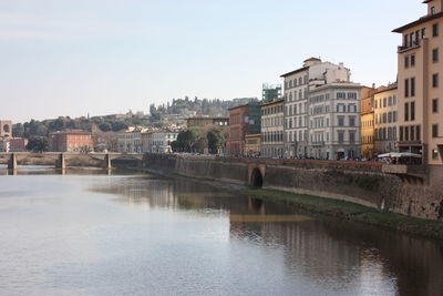 Bridge over river by buildings in city against sky