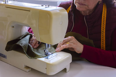 Midsection of woman working on sewing machine