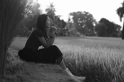 Side view of woman sitting on field