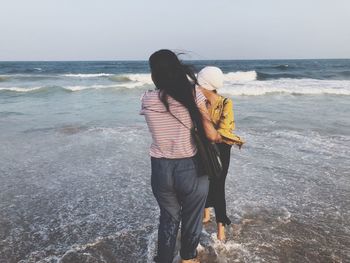 Rear view of women standing at beach