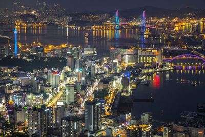 High angle view of illuminated buildings by river at night