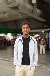 Portrait of young man standing at railroad station