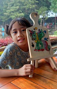 Granddaughter with her painting on a wooden board , during a weekend in lembang bandung