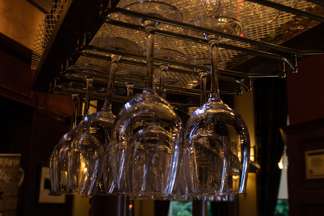 hanging, indoors, no people, lighting equipment, illuminated, low angle view, ceiling, light, focus on foreground, close-up, rack, glass - material, transparent, in a row, glowing, electricity, electric light, upside down, restaurant, decoration