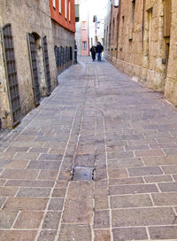 Rear view of man walking on footpath amidst buildings