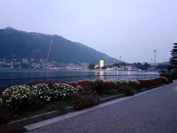 Illuminated city by sea against sky