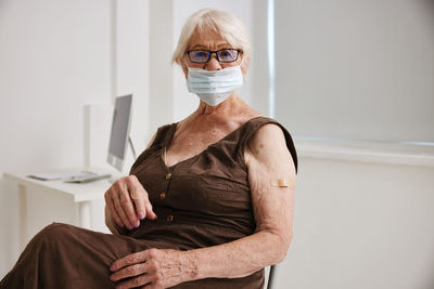 Portrait of senior woman wearing mask while sitting at hospital