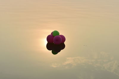 Colorful balloons flying against sky during sunset