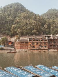 Scenic view of river by buildings against mountain