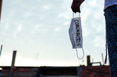 Man holding umbrella hanging against sky