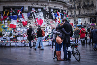 Friends embracing on street against building in city