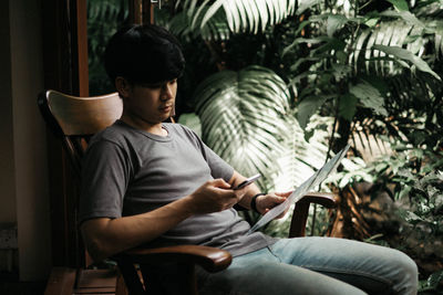 Young man using mobile phone while sitting on chair