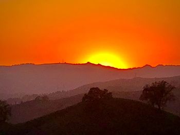 Scenic view of silhouette mountains against orange sky