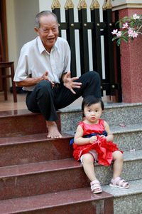 Portrait of grandfather with grandson sitting on steps against house