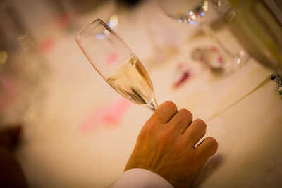 Cropped hand of man holding champagne flute at table