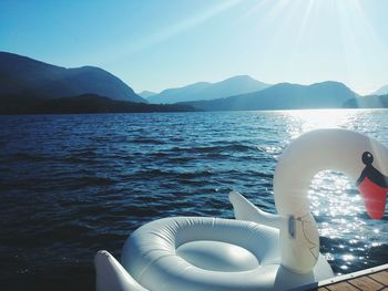 Swan shaped inflatable raft in lake against mountains and clear blue sky during sunny day