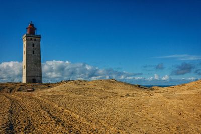 Lighthouse on beach against sky