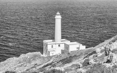 High angle view of lighthouse by sea against buildings