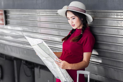 Portrait of young woman standing against wall