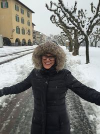 Full length of smiling woman standing in snow