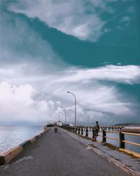 People on road by sea against sky