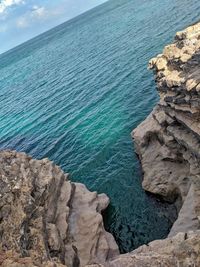 Rock formations on shore against blue sky