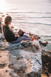 Woman sitting on rock at beach