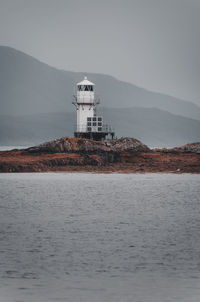 Lighthouse by sea against sky