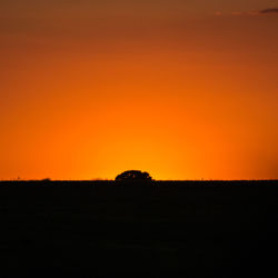Scenic view of silhouette field against orange sky