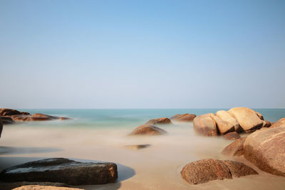 Rocks on beach against clear sky